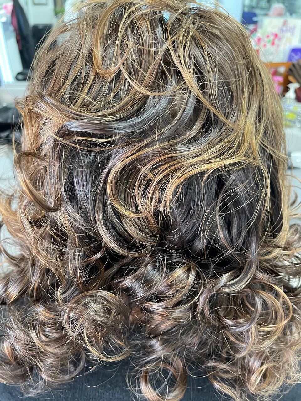Voluminous brown curls lit with caramel highlights