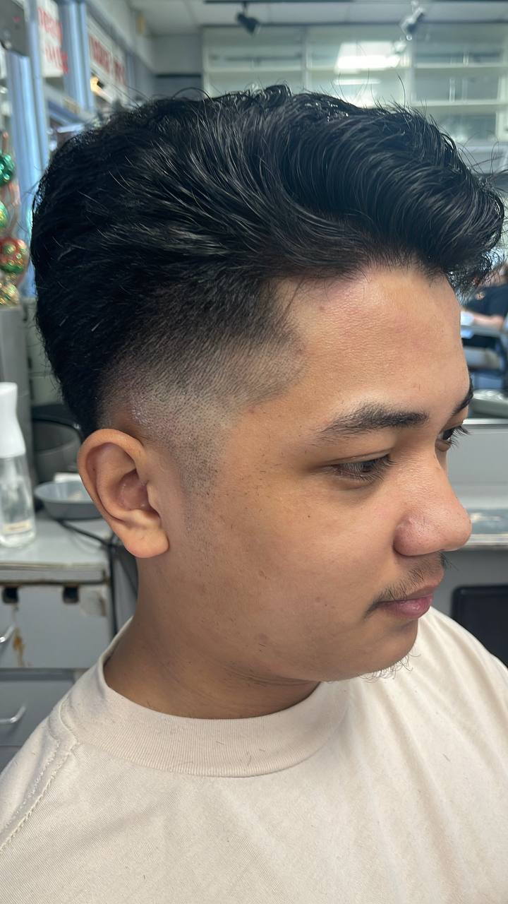 Dark pompadour swept back over a clean low fade